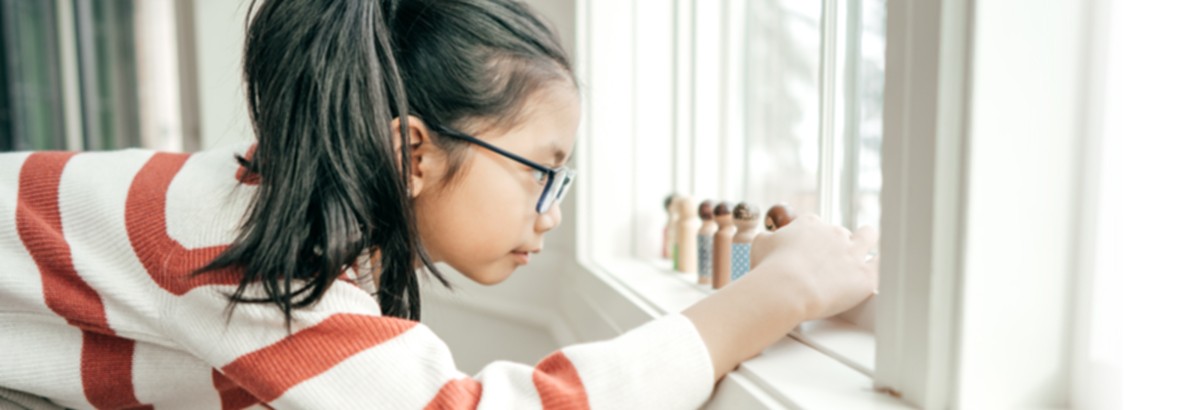 child focused on figurines in windowsill